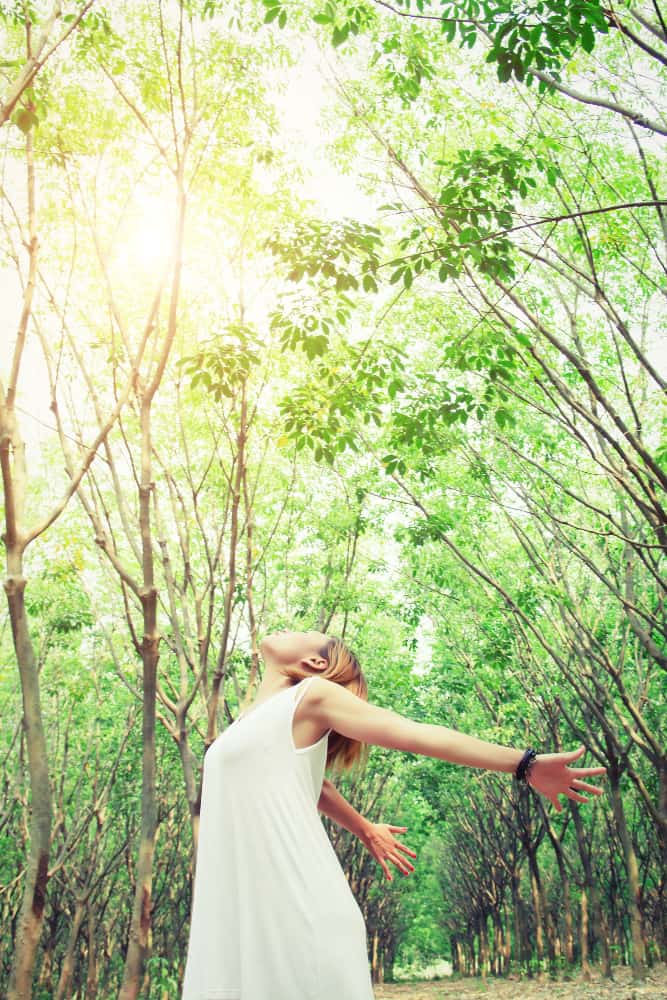 woman with dress in forest enjoying the fresh air